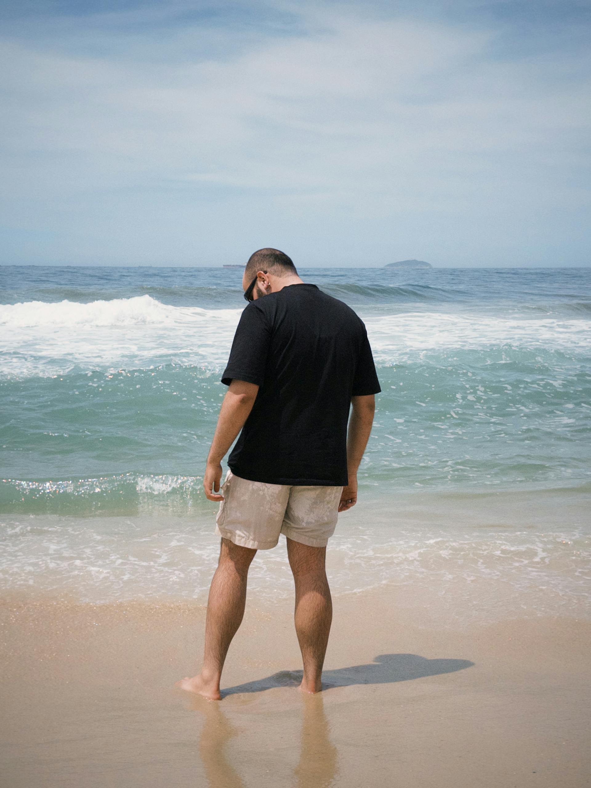 A solitary figure strolls along Ipanema Beach, Rio de Janeiro, enjoying a serene ocean view.